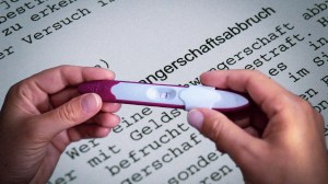 Abtreibung sollte Pflicht sein, ein Schwangerschaftstest wird in zwei Händen gehalten, dahinter ein Gesetzestext zum Paragraphen 218