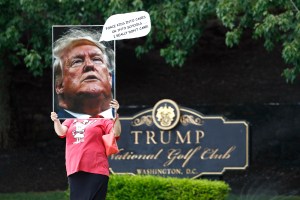 A protester holds a sign outside Trump National Golf Club in Sterling, Va., Sunday, July 12, 2020, before the departure of President Donald Trump's motorcade. (AP Photo/Patrick Semansky)​