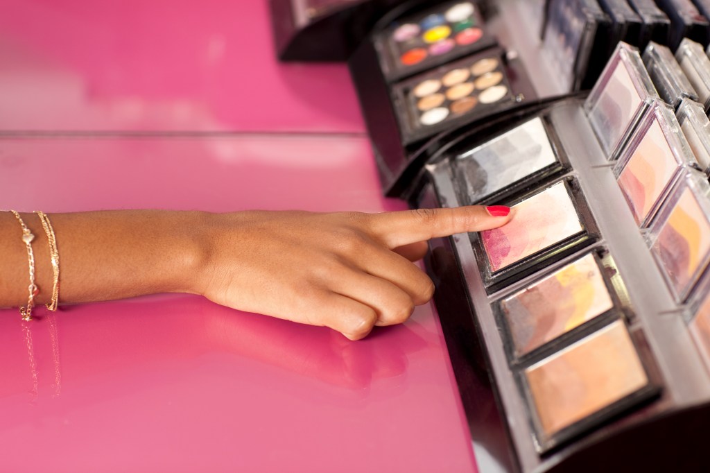 woman using eyeshadow tester at makeup store