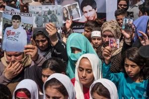 Yazidi women holding pictures of loved ones.