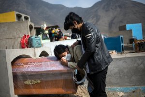 Alberto Alonso comforts his mother Candelaria Salvador crying over the coffin of her husband Joaquin Alonso, 58, who they said died of COVID-19, as they bury him at the cemetery "Martires 19 de Julio" in Comas on the outskirts of Lima, Peru, Tuesday, July