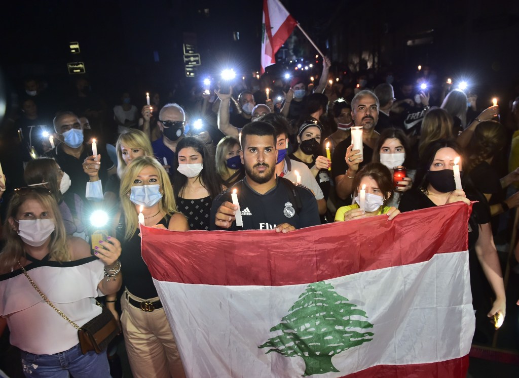 Lebanese people light candles as they gather around the site of explosion