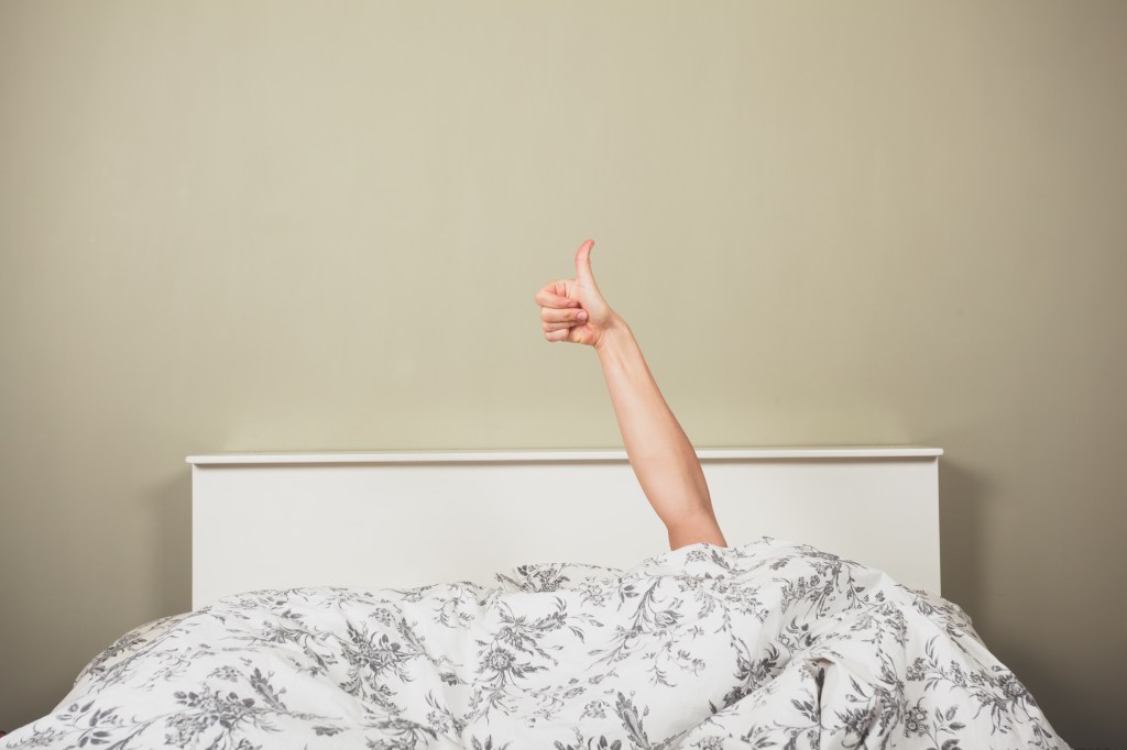 Person in bed giving thumbs up