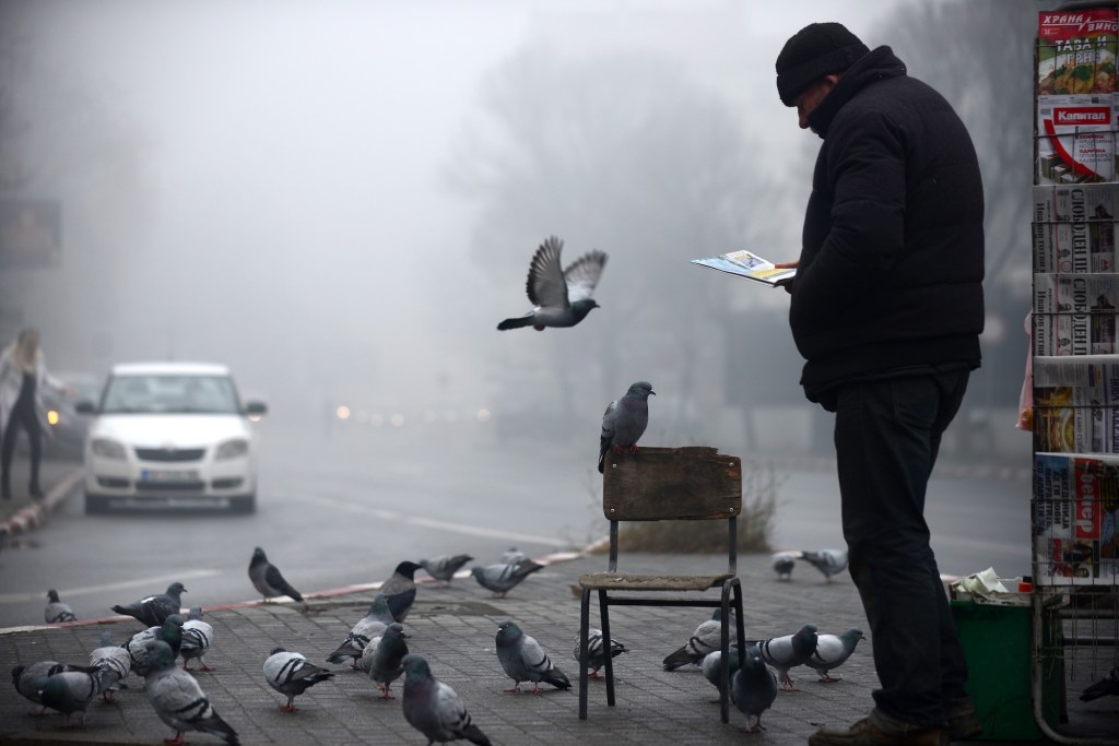 A man reads a newspaper in heavy fog and smog in Skopje, North Macedonia, one of the most polluted cities in the world.