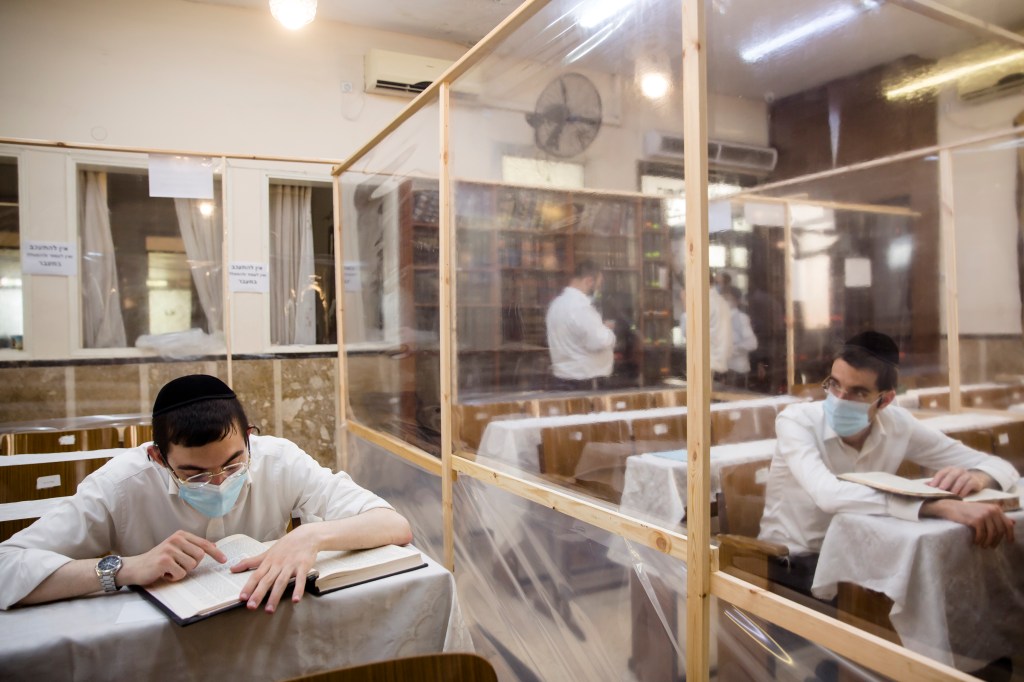 Ultra Orthodox Jewish men study in a synagogue fitted with plastic sheets amid the Coronavirus pandemic ahead of Rosh Hashanah​.