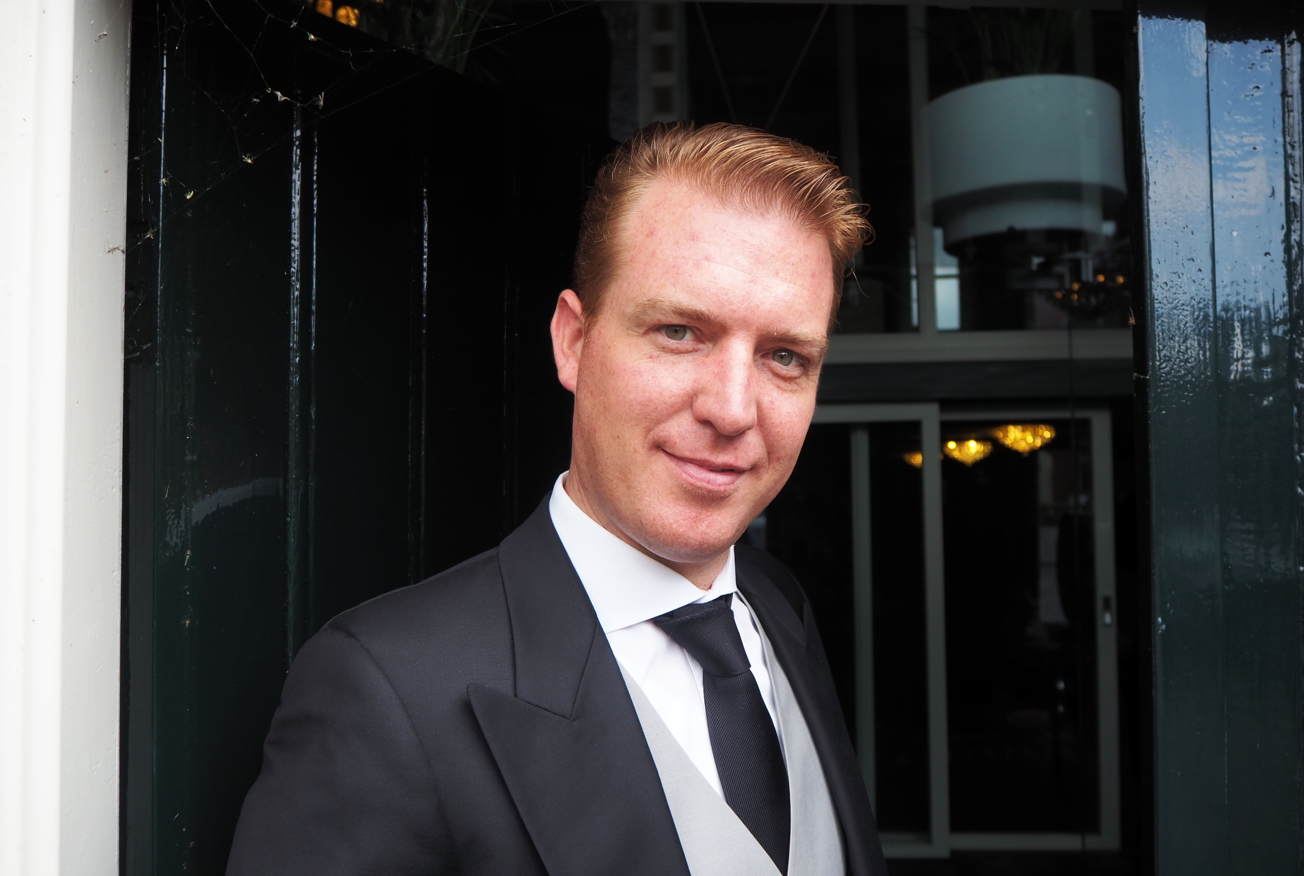 Close-up of André Meester at the door. Short strawberry blond hair, watery eyes.