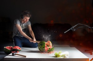 Ronnie van der Veer smashing a watermelon with a bat in front of a microphone. Watermelon juice is splattered on the camera, like blood.