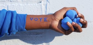 hand with vote written on it holding blue beauty blenders