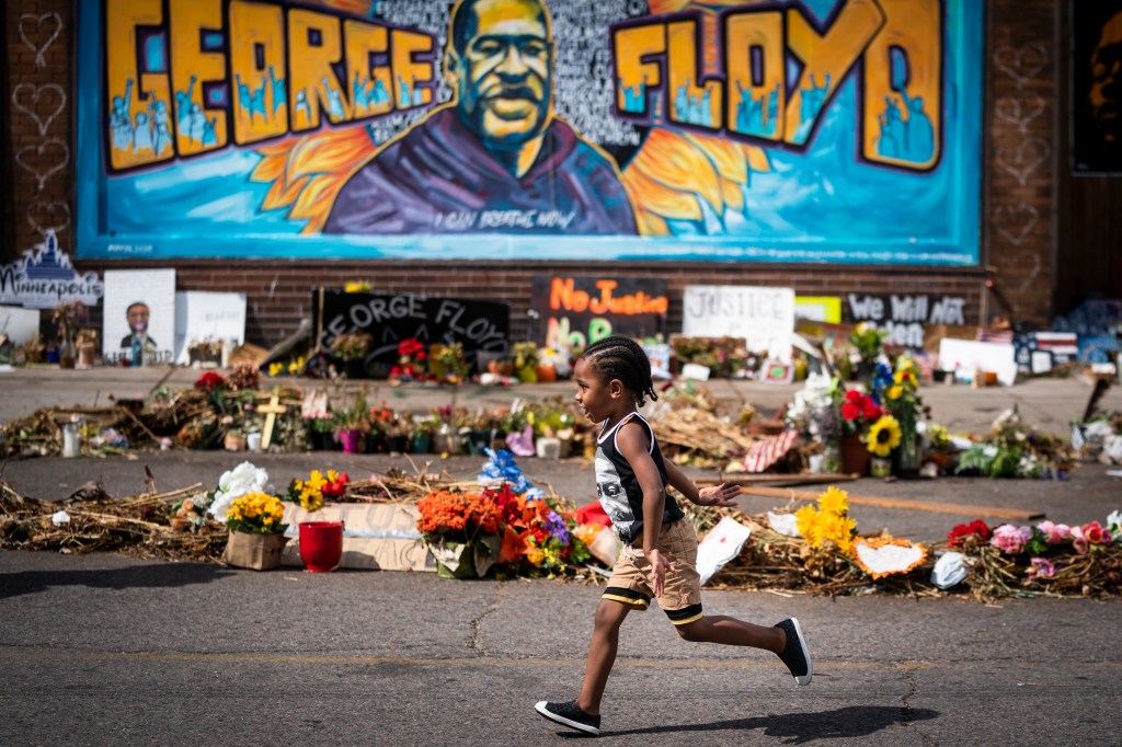 Carter Sims, 3, of Pine Island, Minn., runs past a mural at the George Floyd memorial outside Cup Foods, Thursday, June 25, 2020, in Minneapolis.  (Leila Navidi/Star Tribune via AP)