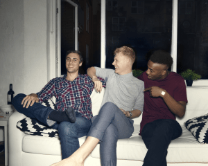 Three young people sit on a sofa.