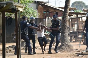 Yopougon municipal police officers arrest a man during a protest against the third term of Ivory Coast President Alassane Ouattara.