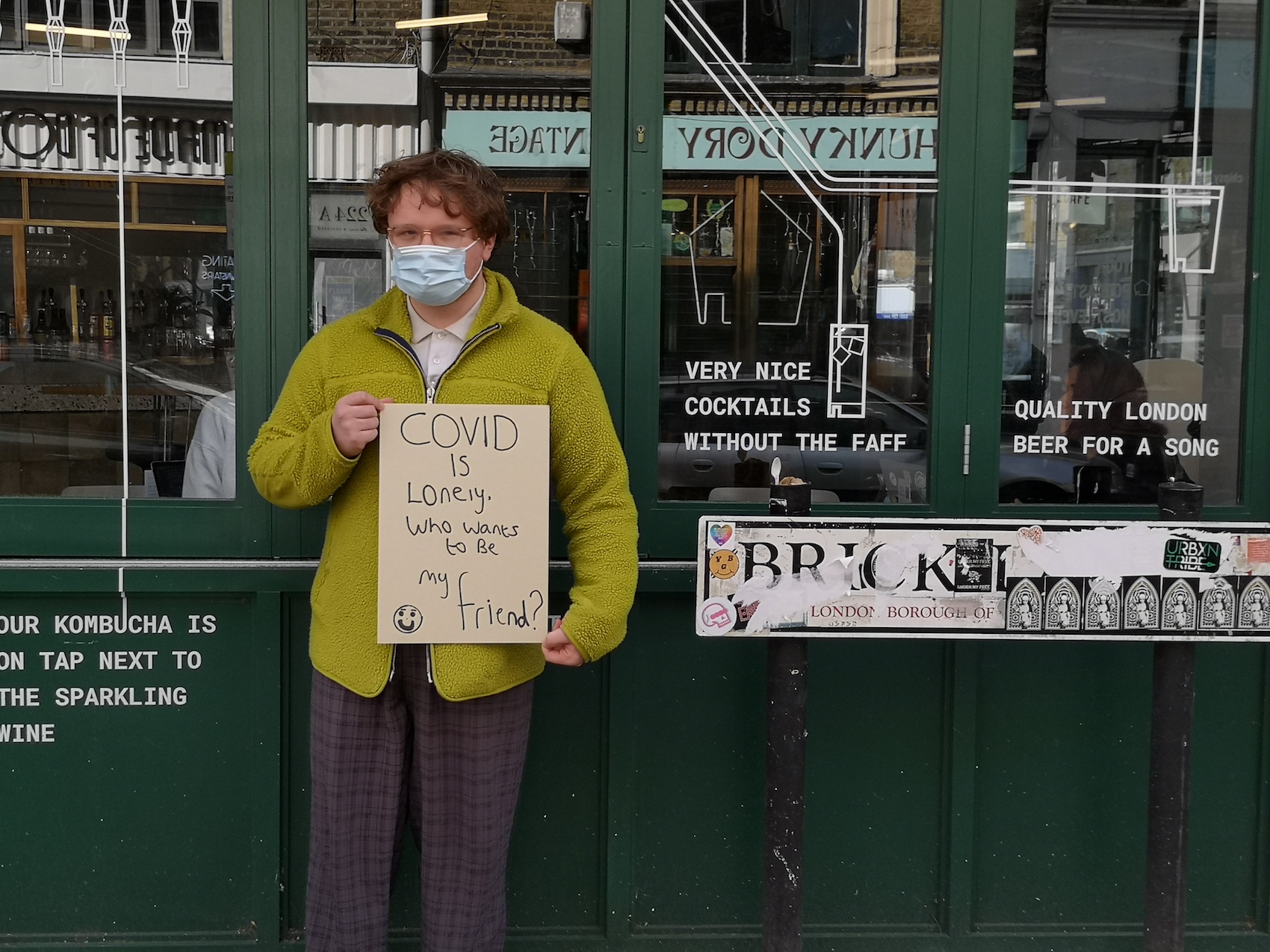 Standing outside in public with a sign asking to make friends