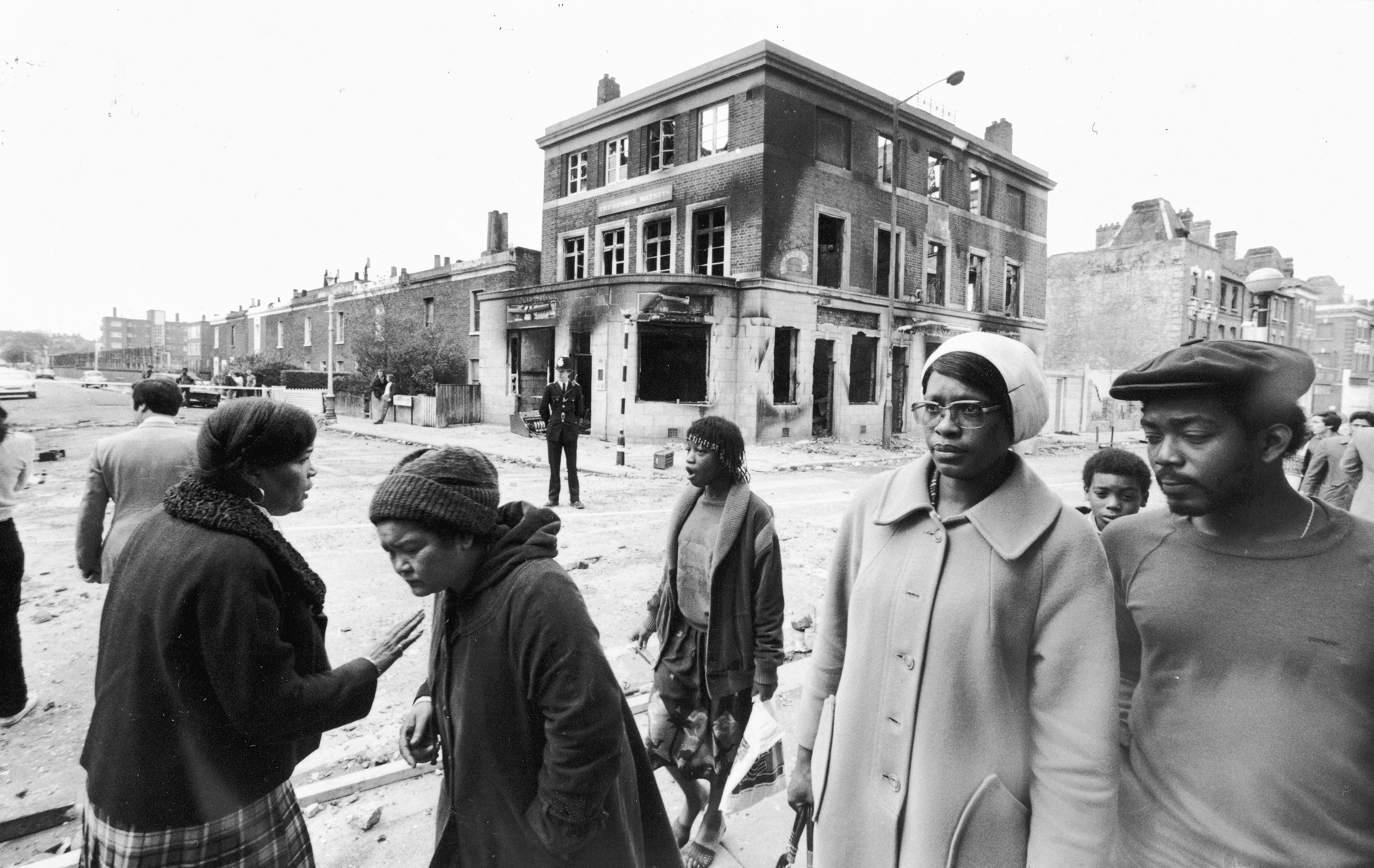 Local residents walk past a burnt out pub in Brixton after a second night of rioting in the area, 13th April 1981. (Photo by Keystone/Hulton Archive/Getty Images)