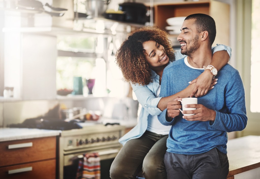 Two people hug in the kitchen at home