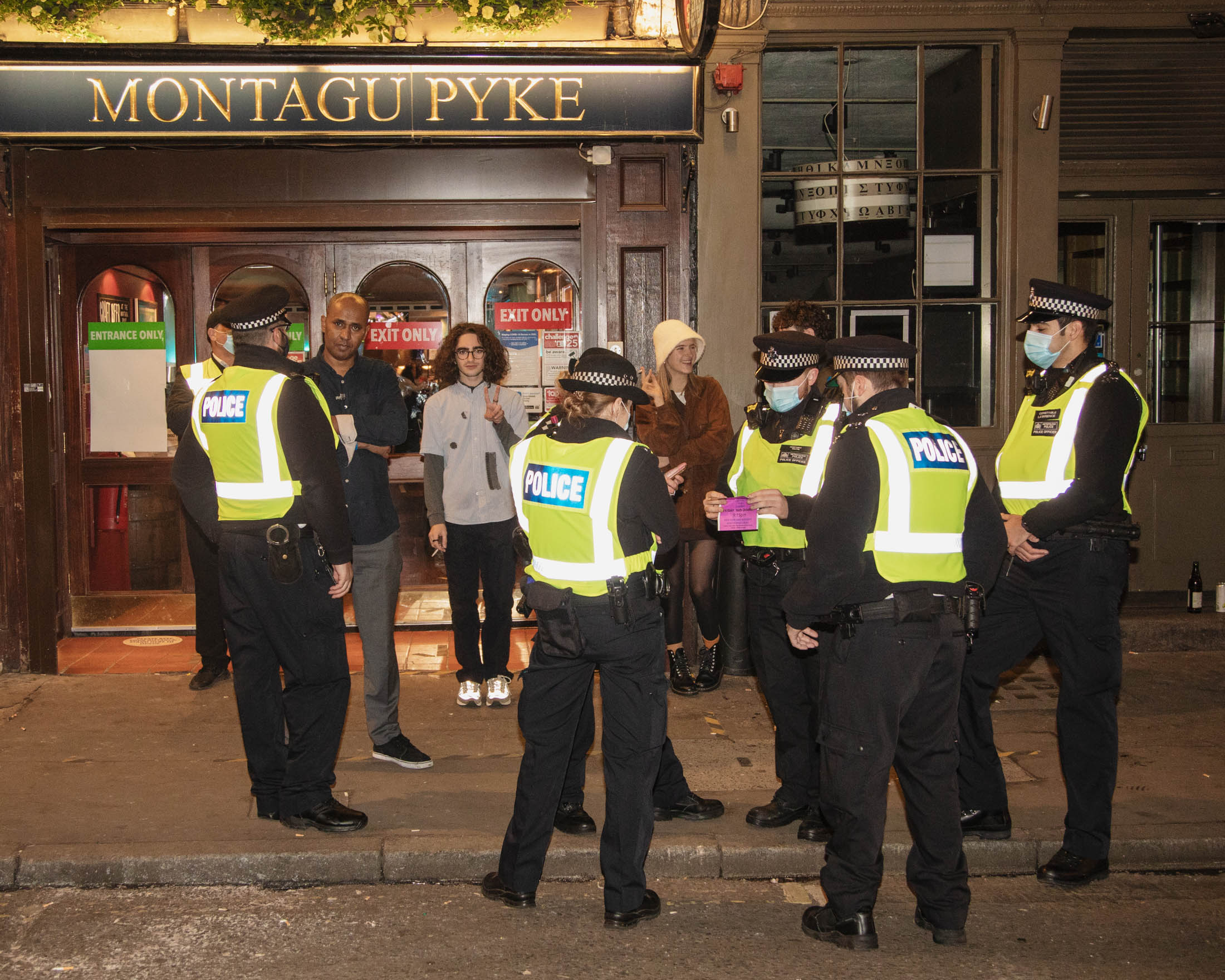 Police and drinkers outside the Montagu Pyke in Soho in London one the last night before new Tier 2 lockdown measures