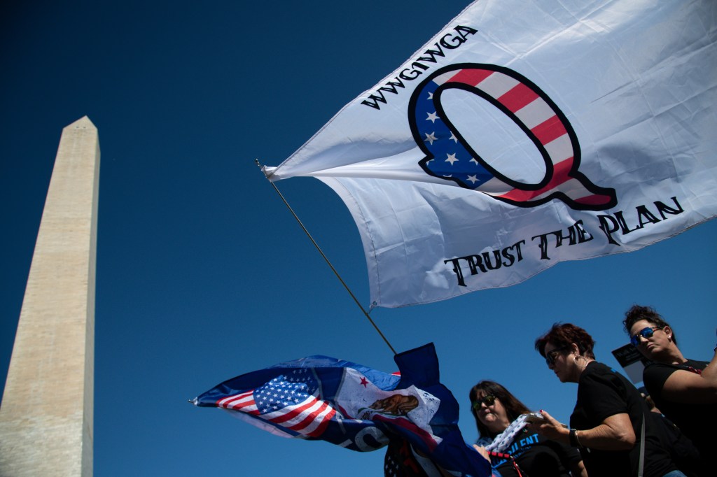 A protester waves a QAnon flag near the Washington Monument, as part of the Unsilent March, in Washington, D.C., on October 3, 2020 (Graeme Sloan/Sipa USA)(Sipa via AP Images)​