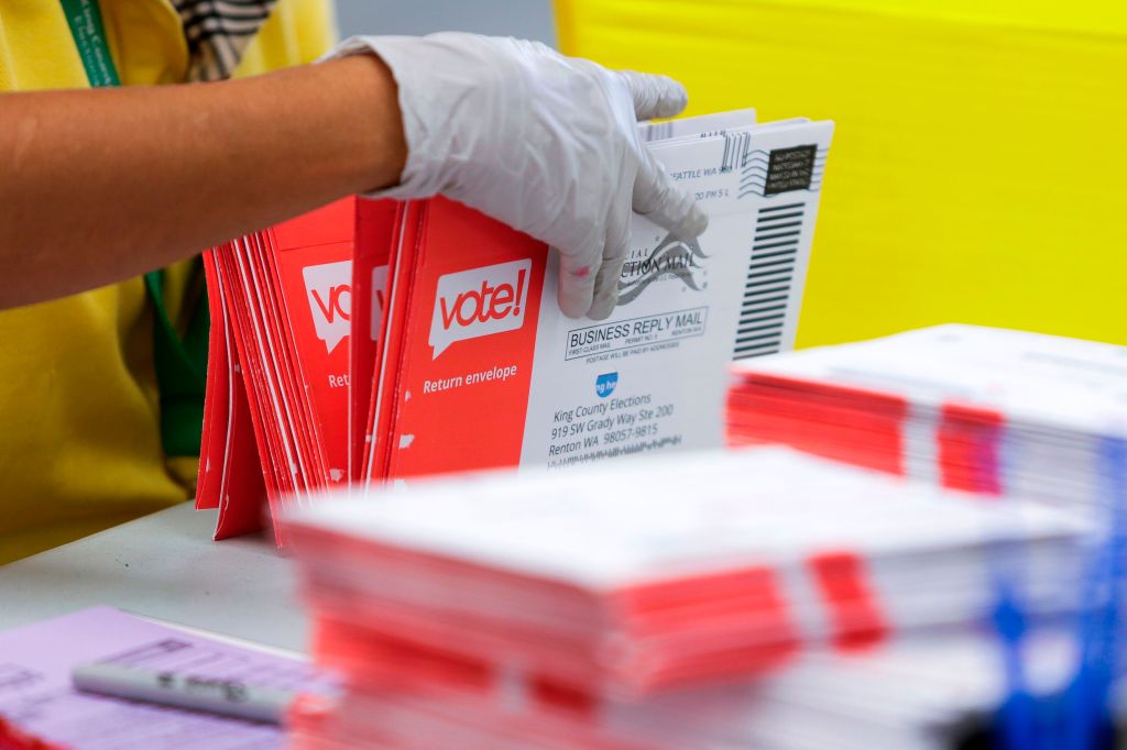 Person wearing a glove handling ballots.