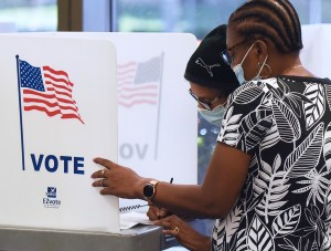 Women wearing face masks fill out vote-by-mail ballots at the Orange County Supervisor of Elections office on October 15, 2020 in Orlando, Florida. (Photo by Paul Hennessy/NurPhoto via AP)​