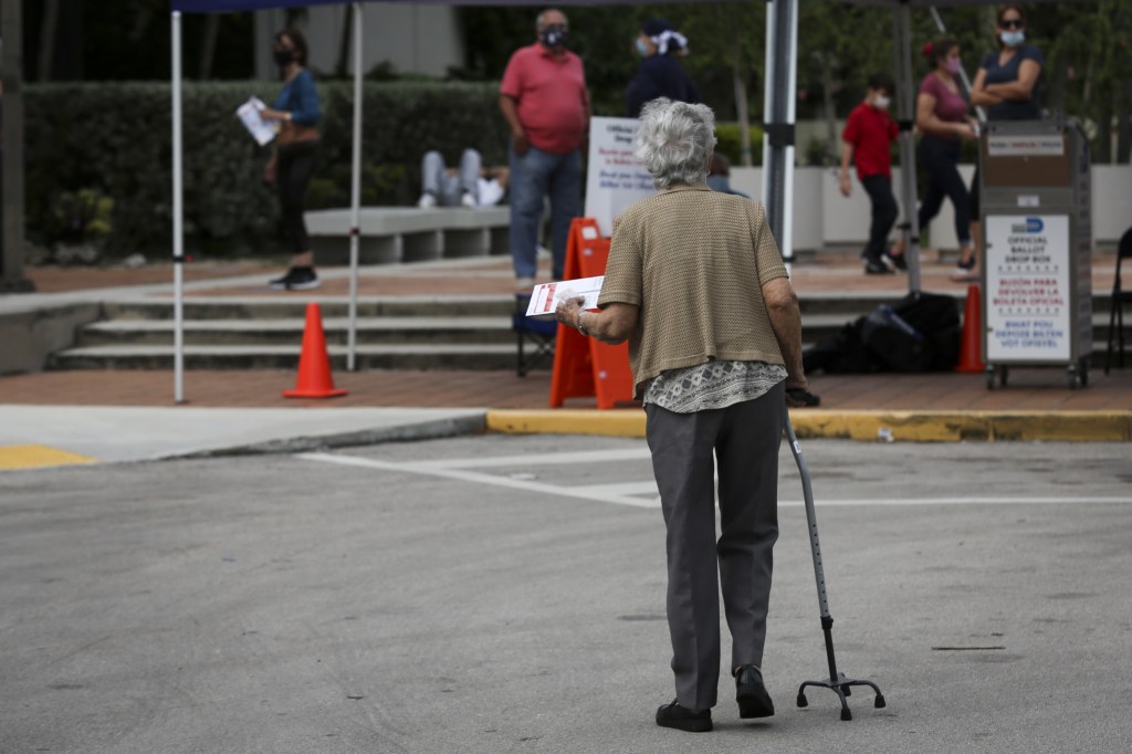 A voter walks to cast a ballot at a drop box at an early voting polling location for the 2020 Presidential election in Miami, Florida, U.S., on Monday, Oct. 19, 2020.