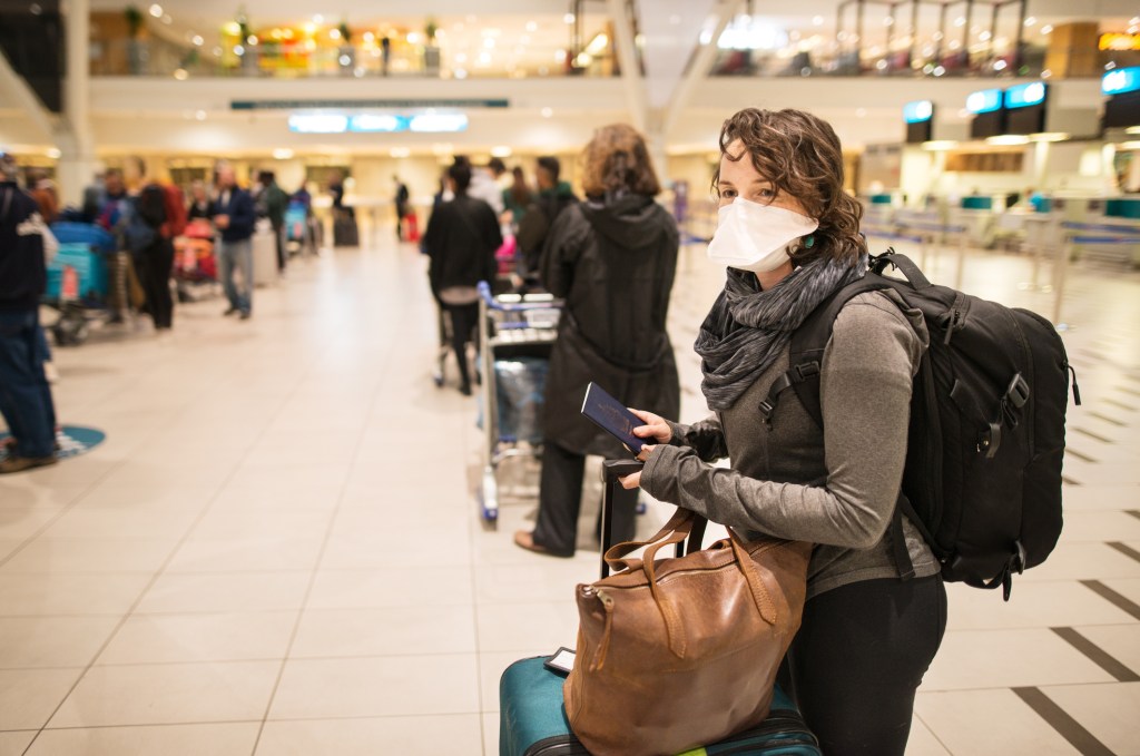 Woman waiting in a long line for a flight wearing a N95 face mask during a global pandemic