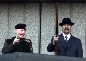 Iraqi President Saddam Hussein (R) and the vice president of the ruling Revolutionary Command Council, Izzat Ibrahim al-Duri, attend a military parade at Baghdad's Victory Square 31 December 2000​.