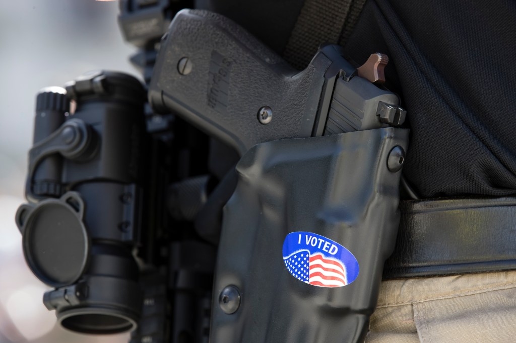 A gun rights advocate with an "I VOTED" sticker on his holster gathers with others for an annual rally on the steps of the state Capitol in Harrisburg, Pa., Monday, May 6, 2019. (AP Photo/Matt Rourke)