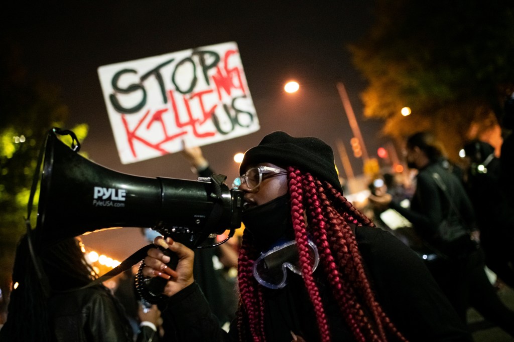 A protester yells into a megaphone in front of the Fourth District police station during a protest in memory of Karon Hylton (Graeme Sloan/Sipa USA)(Sipa via AP Images)