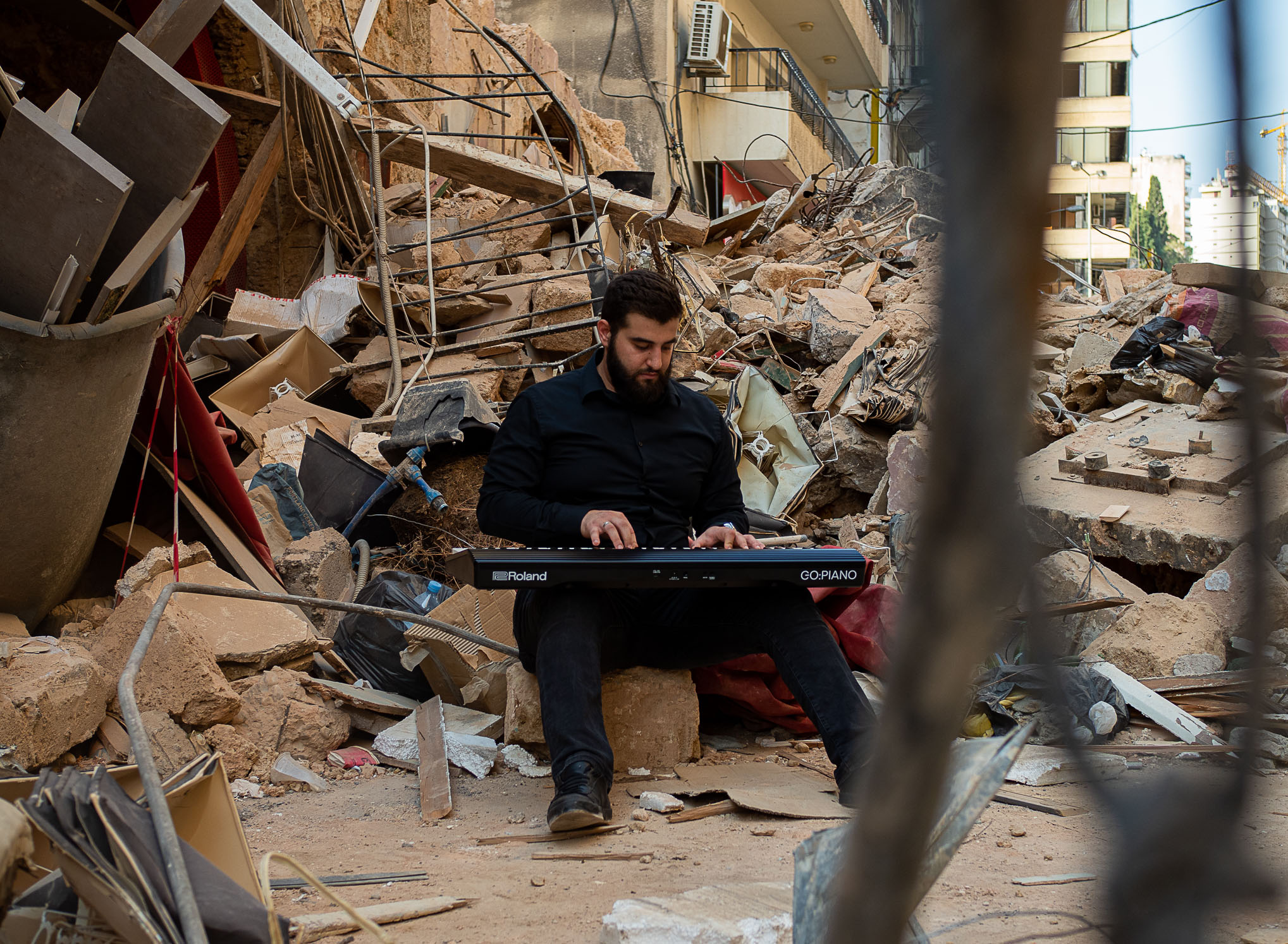 Nightingales of Beirut, Eveline Gerritsen. Hussein playing keyboard in the middle of rubble.