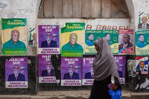 A woman walks by a wall of political posters in Zanzibar.