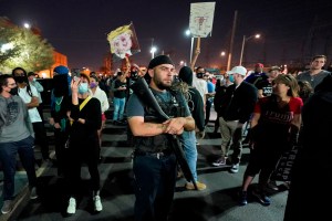 President Donald Trump supporters rally outside the Maricopa County Recorder's Office, Wednesday, Nov. 4, 2020, in Phoenix as two counter-protesters stand in the rear. (AP Photo/Matt York)