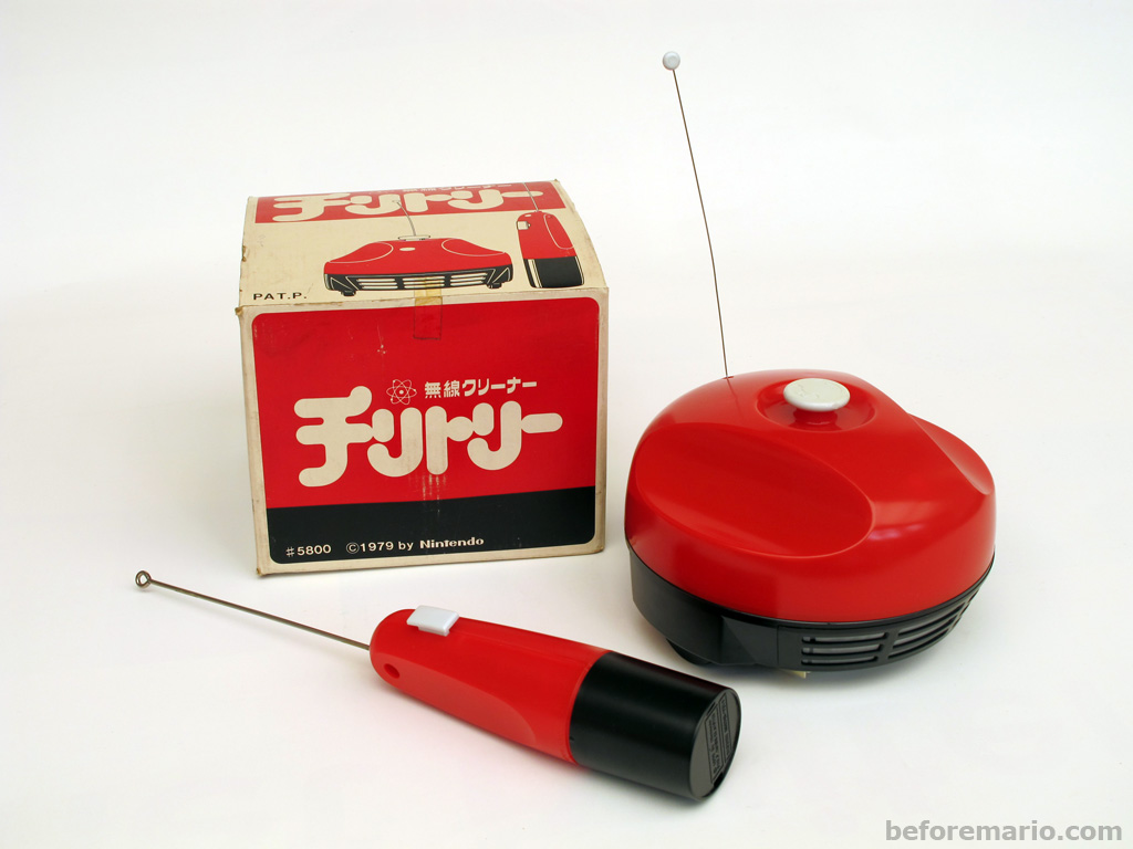 A bright red and black plastic remote control and vacuum cleaner set, with simple 60's Star Trek or Jetsons aesthetics: big buttons, big antennae everywhere.