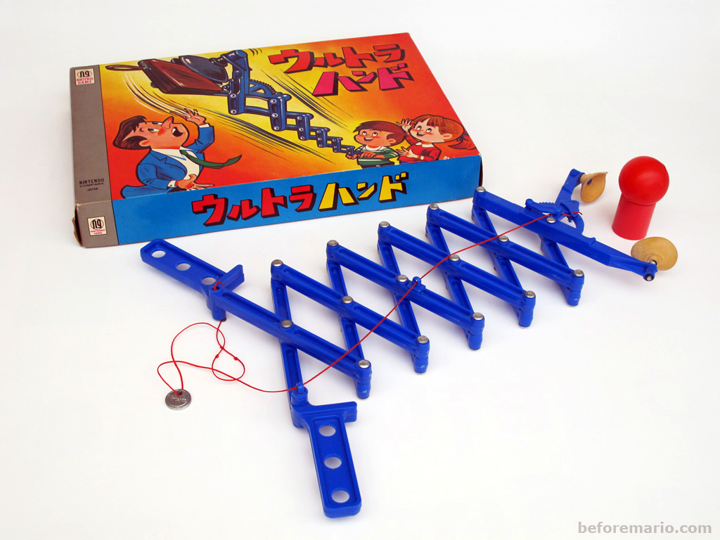 A blue plastic articulated gripper clip attached a scissor-extending arm, with age-yellowed suction cups at the end. This is the Nintendo Ultra Hand: its box depicts a businessman looking dismayed as his smiling children use the device to lift his wallet.