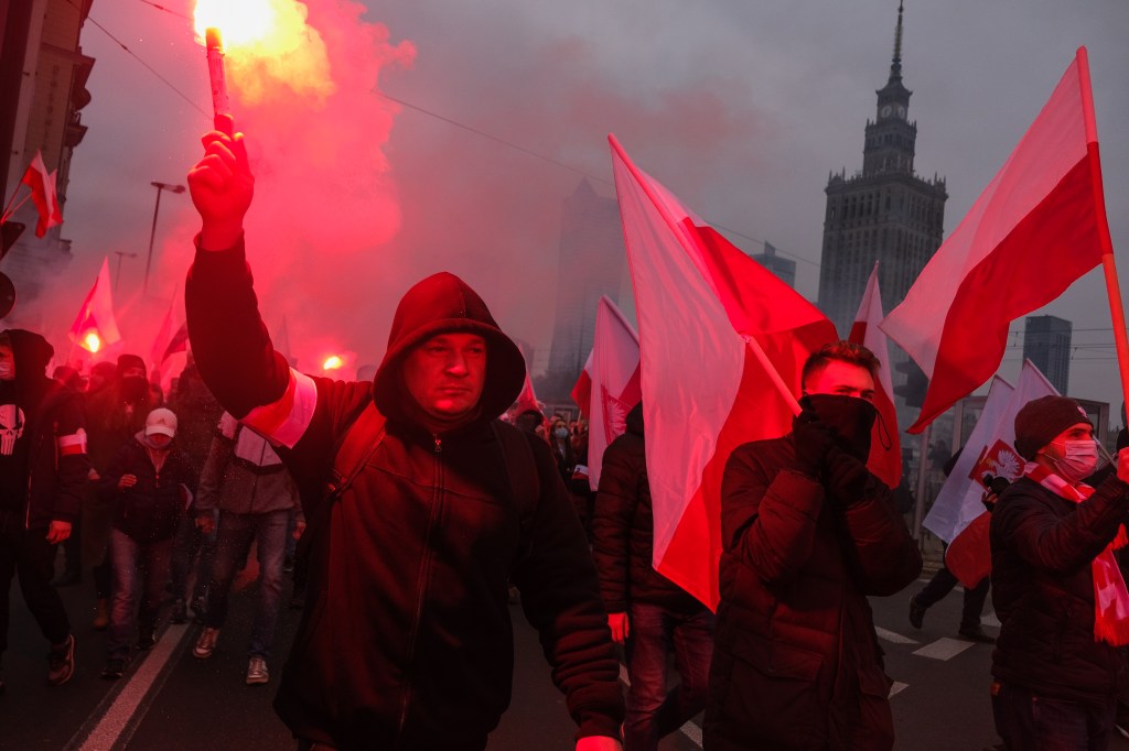 A man holds a red flare during Poland's Independence Day march.