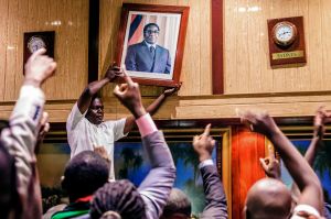 People remove, from the wall at the International Conference centre, where parliament had their sitting, the portrait of former Zimbabwean President Robert Mugabe after his resignation on November 21, 2017 in Harare​.