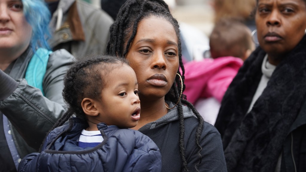 Dominique Walker, a member of the Moms 4 Housing activist group, holds Amir Morrow, 1 year old, before announcing a deal the organization reached with Wedgewood, the property owner of the Magnolia Street home the group squatted in for 58 days, at Frank H.