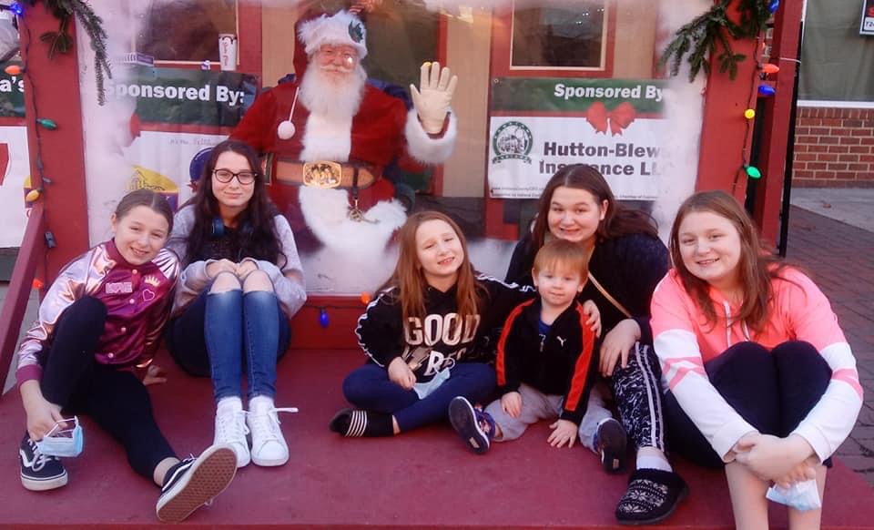 A professional Santa Claus with a family, behind a plexiglass barrier.