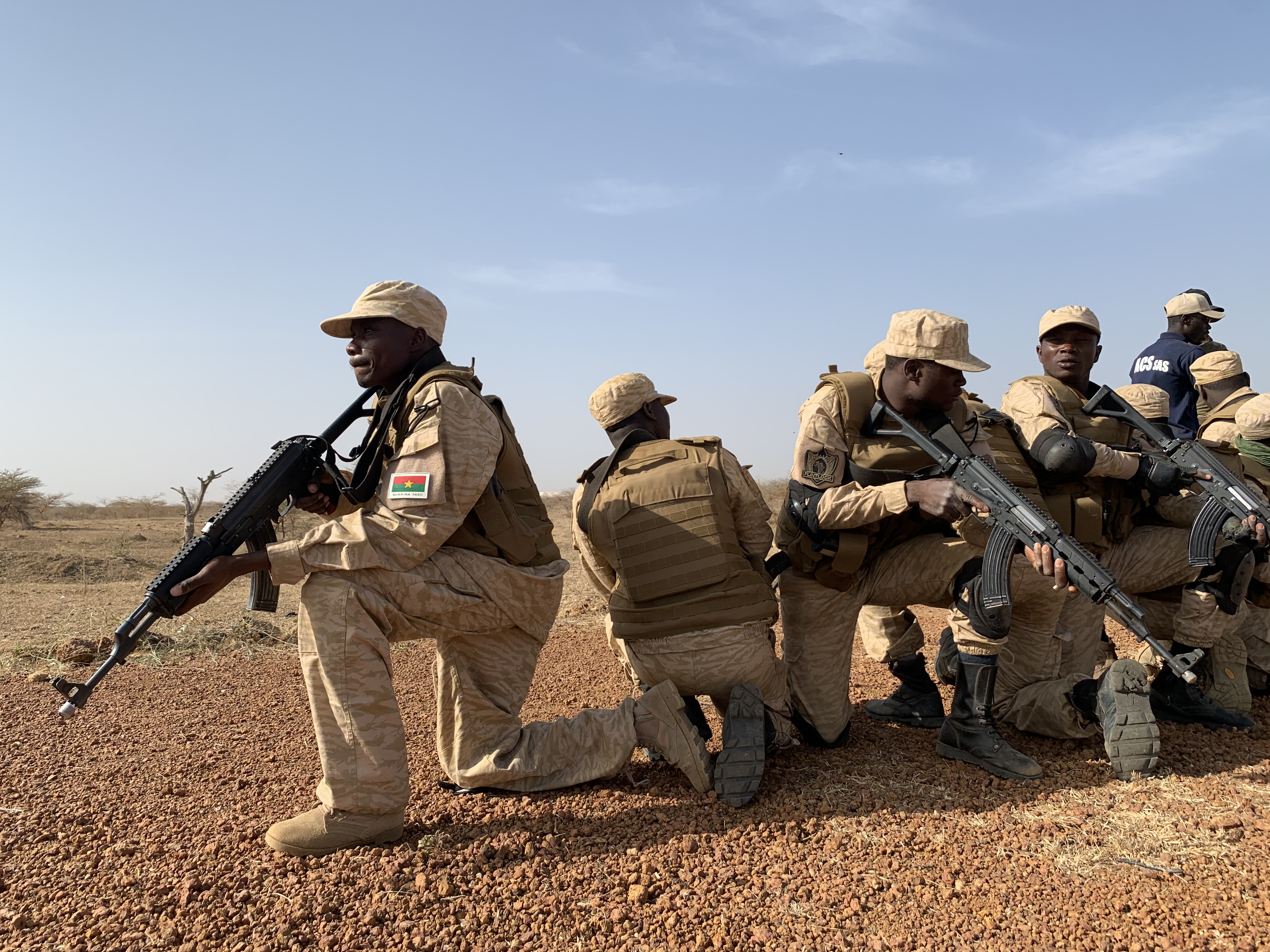 Soldiers kneel on the grounding holding guns.