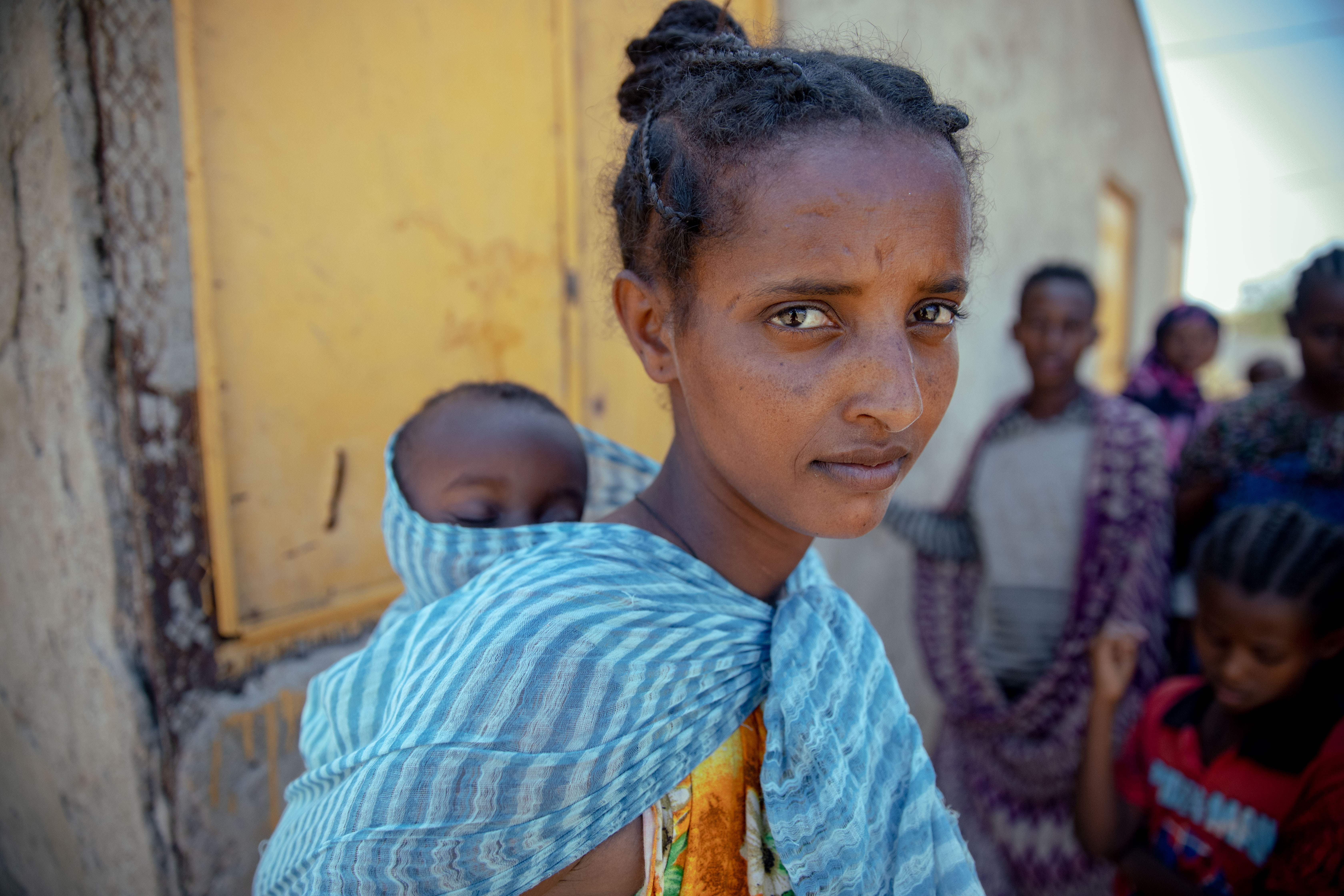 Freweyni Kiros 20 with 1 year old baby. Women queue at a makeshift meical center for babies and yougn children in Village 8 refugee settlement in Eastern Sudan.