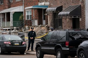 A police officer stands watch in front of a house, right, which was the scene of a shooting in The Bronx, Friday, Dec. 4, 2020 in New York. A suspect in the shooting of a state trooper in Massachusetts was killed during a shootout with U.S. marshals in Ne