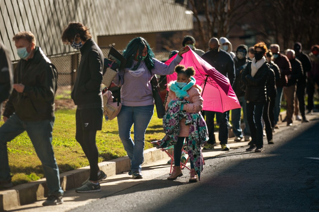 Voters wait in a long line to vote at the Buckhead library in Atlanta on the first day of In-person early voting for the Georgia Senate runoff election on Monday, Dec. 14, 2020 in Atlanta, GA.