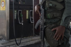 A member of the Bolivarian National Guard (GNB) holds a gun while standing guard outside a gas station in Caracas