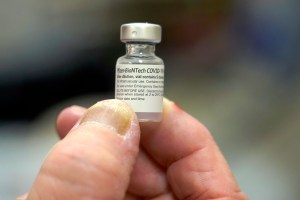 Michael Moore, a registered nurse with the Mississippi State Department of Health immunization program, holds an empty vial of the first round of the Pfizer COVID vaccination, that was injected into the arm of one of the state medical leaders, Wednesday,