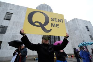 A woman holds a QAnon sign as reopen protesters demonstrate at the capitol in Salem, Ore., on May 2, 2020. Governor Kate Brown announced a plan yesterday that could see some parts of the state reopen by May 15. (