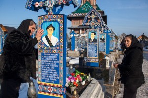 Trauernde Frauen an blauen Grabtafeln auf einem Friedhof in Rumänien