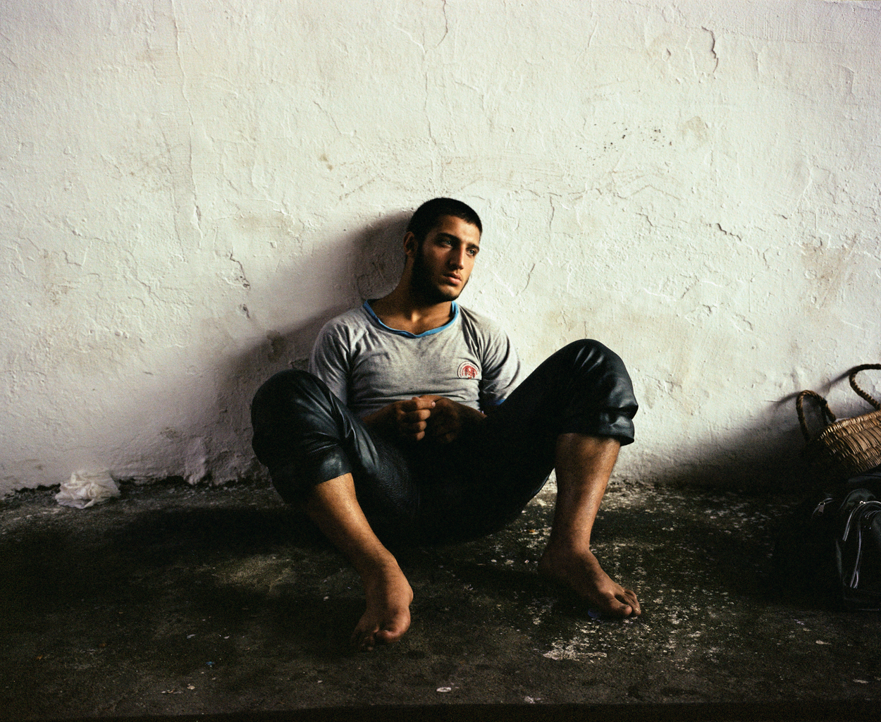 Mathias Depardon - Transanatolia. A man sitting on the ground barefoot, looking off camera.