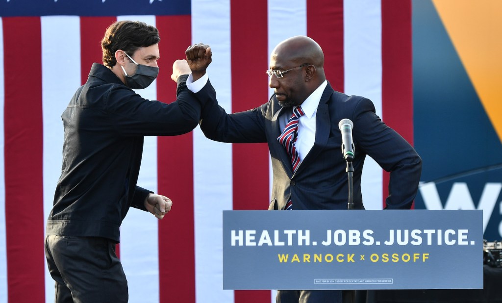 Georgia Democratic Senate candidates Jon Ossoff and Raphael Warnock greet each other onstage at New Birth Church on December 28, 2020 at New Birth Church in Stonecrest, Georgia.