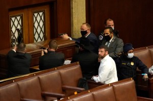 U.S. CAPITOL POLICE OFFICERS POINT THEIR GUNS AT A DOOR THAT WAS VANDALIZED IN THE HOUSE CHAMBER DURING A JOINT SESSION OF CONGRESS ON JANUARY 06, 2021 IN WASHINGTON, DC.