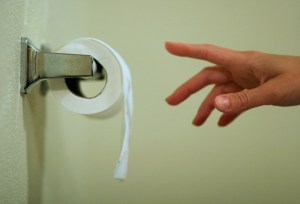 Close up of hand reaching for toilet paper