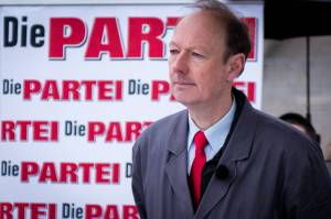 Martin Sonneborn vor einem Banner der PARTEI