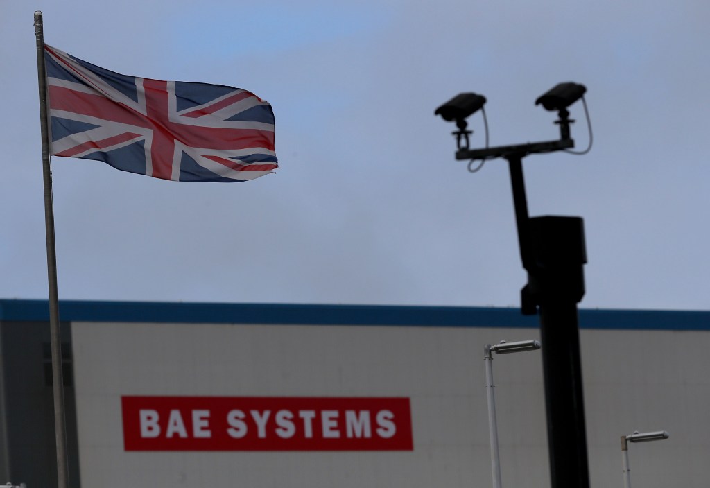 A union jack flag flies in front of a building with the BAE Systems logo